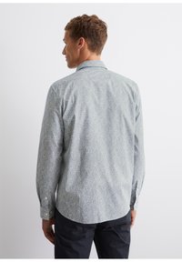 Long-sleeve button-up shirt in light blue with a textured geometric pattern, featuring a classic collar and single-button cuffs.