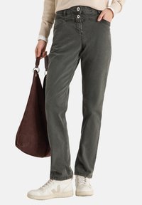 Szare spodnie dżinsowe z zapięciem na dwa guziki, przednimi kieszeniami i luźnym krojem. Do tego brązowa torba i białe trampki.