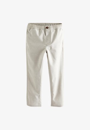 Beige broek met elastische tailleband, knoop aan de voorkant, rechte pijpen en zijzakken, plat liggend op een witte achtergrond.