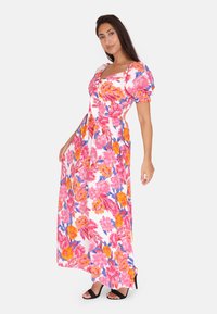Abito lungo con maniche a palloncino corte, stampa floreale in rosa, arancione e blu su sfondo bianco. Scende fino alle caviglie, scollatura aderente, forma rilassata.