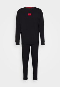 Conjunto de sudadera y pantalones de algodón negro con mangas largas y puños, que presenta un pequeño logo rectangular rojo en la parte frontal.