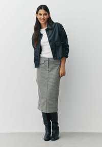 Svart läderkort jacka, vit t-shirt, houndstooth pennkjol, knähöga svarta stövlar; eleganta material och skräddarsydd passform.