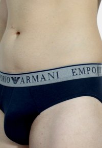 Slip da uomo blu navy realizzati in tessuto liscio, con una fascia elastica grigia in vita con il marchio "Emporio Armani".