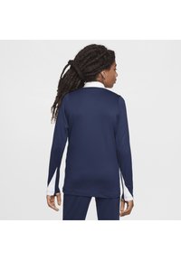 Marineblauwe sporttop met lange mouwen, witte kraag en zijaccenten. Gladde, lichte stof met een aangesloten ontwerp.