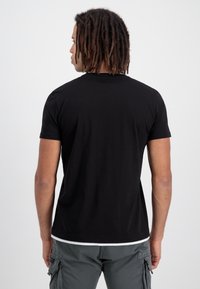 Tricou negru cu mânecă scurtă, cu decolteu rotund și un design mulat, realizat dintr-un material moale, expus din spate.