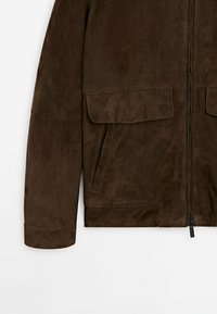 Bruine suède jas met ritssluiting, zijzakken en twee klepzakken aan de voorkant, met een gladde textuur en een ontspannen pasvorm.