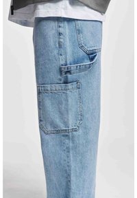 Pantalones cargo de denim azul claro con bolsillos laterales y un acabado texturizado. Ajuste relajado con costuras visibles y detalle de bolsillo doblado.