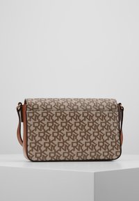 Hnědá vzorovaná crossbody taška s texturovaným plátnem a koženými akcenty. Má magnetický klapkový uzávěr a nastavitelný popruh.