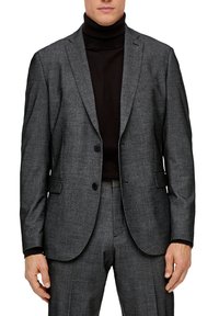 Sivi blazer od vune sa strukturnim krojem, reverima s usjekom, dva dugmeta i teksturiranim završetkom. Nošen preko crnog roll-kragne.