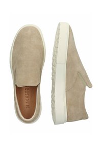 Béžové semišové boty na slip-on s elastickými bočními akcenty, bílou gumovou podrážkou a hladkým, texturovaným povrchem. Mají prostornou špičku.