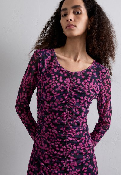 Robe à manches longues avec un col rond, présentant un motif floral rose sur un fond marine, avec des détails froncés et une silhouette ajustée.