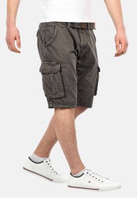 Cargo shorts in dark gray cotton with multiple side pockets, belt loops, and a casual fit. Paired with white sneakers and socks.