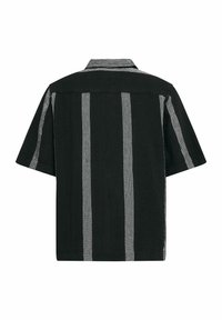 Czarna koszula z krótkim rękawem w białe pionowe paski, luźny krój, miękka tekstura, kołnierzyk i prosta linia hemu.