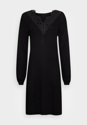 Abito nero lavorato a maglia con maniche lunghe e scollatura a V. I dettagli in pizzo sulla scollatura aggiungono texture. Tessuto morbido con vestibilità rilassata.