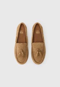 Hnedé semišové loafers s akcentami z príveskami, okrúhlou špičkou a prešívanou podrážkou. Interiér je z béžovej kože s logom značky.