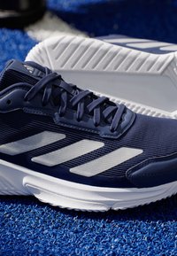 Morska sportowa obuwie wykonane z siateczki i materiałów syntetycznych, z trzema białymi paskami, textured górą i wyściełaną białą podeszwą.