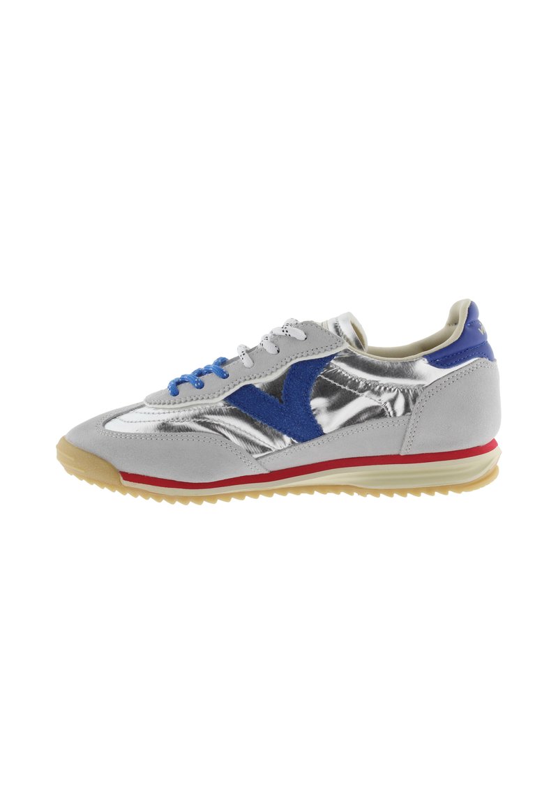 Zapatilla plateada y gris con logo y cordones de ante azul, franja roja en la suela y suela exterior estriada beige, mostrada en perfil lateral izquierdo.