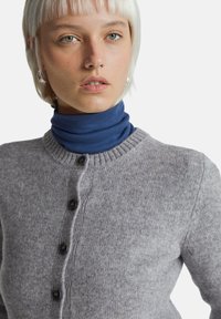 Šedý svetr z pleteného materiálu s kulatým výstřihem a žebrovanými lemy, s černými knoflíky vpředu.