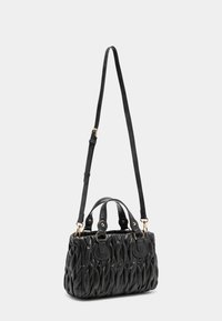 Borsa a tracolla nera trapuntata con una superficie testurizzata, doppi manici e una tracolla staccabile. Accenti in hardware color oro.