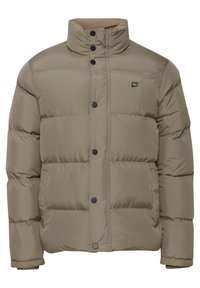 Beige puffer jacket with a high collar, featuring black buttons and a small logo on the left chest. Textured, insulated design with a boxy fit.