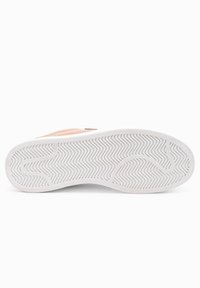 Bílá podešev tenisky se vzorem trakce ve tvaru cik-cak. Semišový svrček v jemné broskvové barvě s hladkým povrchem a minimálním logem.