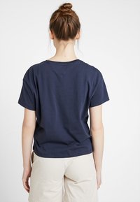 Mörkblå bomullströja med korta ärmar, rund halsringning och avslappnad passform. Enfärgad design med en fåll som faller något vid midjan.