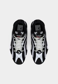 Ζευγάρι αθλητικών παπουτσιών Reebok σε μαύρο και λευκό με λευκά κορδόνια, σε εικόνα από πάνω, με φόντο απλό λευκό.