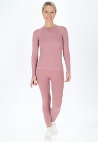 Top a maniche lunghe rigato rosa con leggings aderenti abbinati. L'outfit presenta una texture liscia e un classico scollo rotondo.