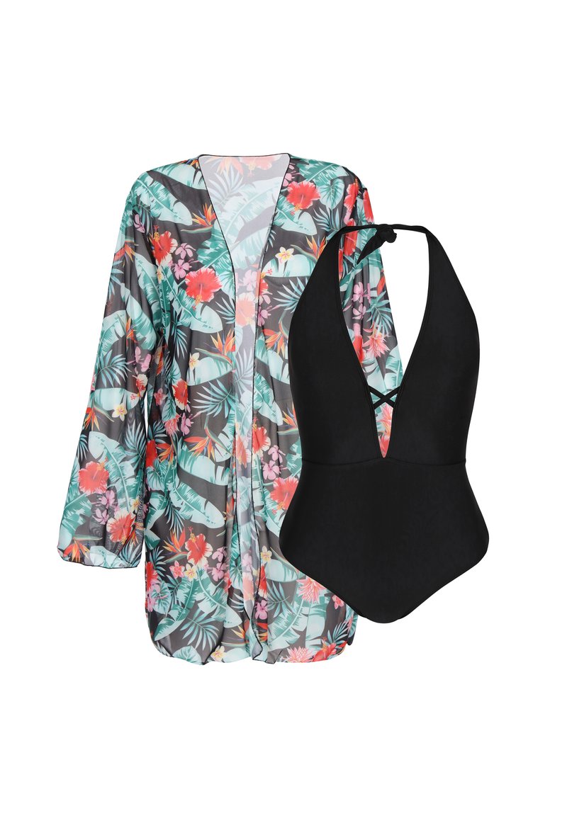Copricostume floreale con foglie verdi e fiori rossi sopra un costume da bagno nero a collo alto. Il copricostume è trasparente, leggero e si drappeggia in modo morbido.
