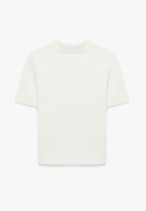 T-skjorte med korte ærmer i ribbet stof i lys beige. Har en blød krave og en tætsiddende pasform. Glat tekstur med minimal detaljering.