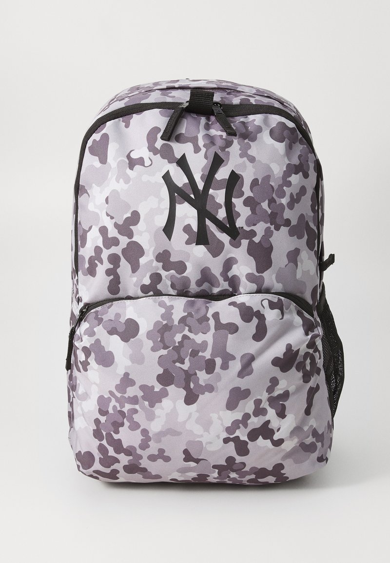 Zaino con motivo camouflage viola, dotato di un logo nero prominente, cerniere in tessuto e tasche laterali in rete. Design durevole e leggero.