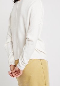 Rundhalsad, långärmad tröja i mjukt vitt material med en texturerad yta, med rak skärning och sömmar i ryggen.