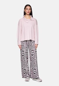 Light pink oversized sweater with a collar, paired with wide-leg black and white checkered pants featuring wavy patterns and accents.