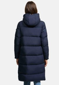 Long navy puffer coat with a hood, featuring horizontal quilted sections, a relaxed fit, and ribbed cuffs. Smooth, matte texture.