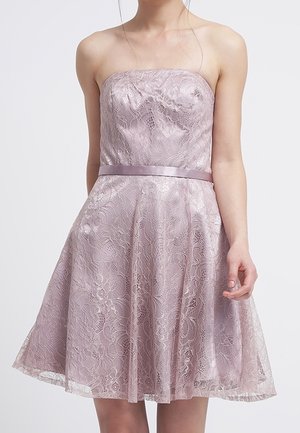 Vestido lavanda sin tirantes hasta la rodilla con superposición de encaje floral y cinturilla de satén en una persona de pie sobre un fondo liso.