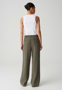 Haut sans manches blanc avec un col rond, assorti à un pantalon ample vert olive avec une taille élastique et deux poches arrière.