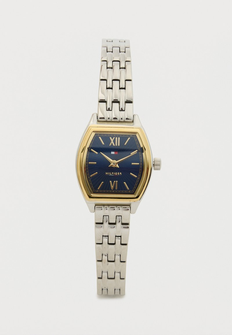 Gold and silver-tone watch with a rectangular face, blue dial, Roman numerals, and linked metal bracelet. Notable logo at 6 o'clock.