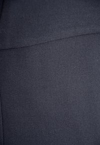 Ciemnoniebieska tkanina o gładkiej fakturze, z delikatnym połyskiem i minimalnym przeszyciem wzdłuż szwu. Materiał wygląda na trwały.