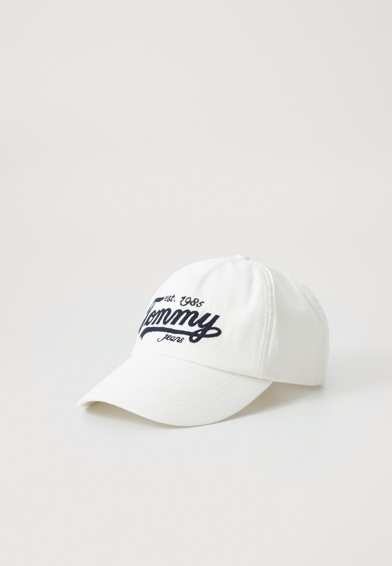 White cotton cap with a curved brim and blue embroidered text reading "Tommy Jeans est. 1985." Simple design with no additional embellishments.