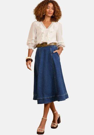 Denim A-line skirt with side pockets, knee-length, and a raw hem. Paired with a white blouse featuring ruffles and lace trim. Brown belt included.