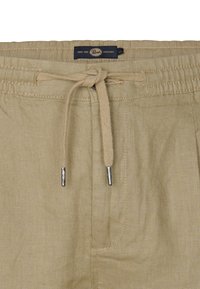 Beige Leinenshorts mit einem elastischen Bund und Kordelzug. Mit einem Etikett mit dem "Peregrine"-Logo und metallischen Aglet-Akzenten.
