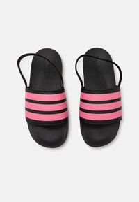 Infradito neri con una larga fascia rosa caratterizzata da tre strisce nere. Texture liscia con una suola piatta e fasce sottili.