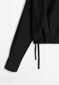 Schwarze, kurze Bluse mit glatter Textur, langen Ärmeln und gebundenen Akzenten am Saum. Verfügt über einen strukturierten Kragen und taillierte Manschetten.