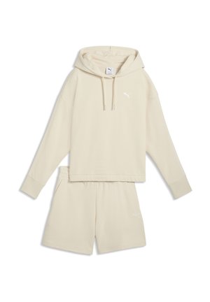 Beige oversized hættetrøje med snore og matchende beige elastiske taljeshorts, begge med små Puma-logoer.