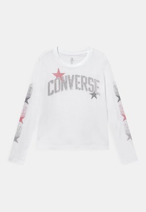 Biała koszulka z długim rękawem z napisem '"CONVERSE"' oraz wzorami gwiazdek w szarym, różowym i czarne kropki na klatce piersiowej i rękawach.