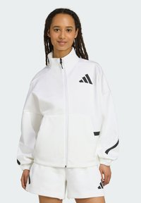 White zip-up jacket made of soft material, featuring black accents and logo. The design includes elastic cuffs and a relaxed fit, paired with shorts.