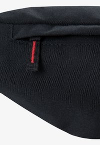 Saco de tecido preto com uma superfície texturizada e um acento de costura vermelha pronunciado perto do topo. O design é minimalista e aerodinâmico.