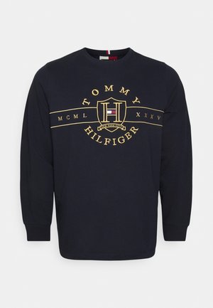 Marineblaues Langarm-T-Shirt aus Baumwolle mit goldgesticktem "Tommy Hilfiger"-Logo und Wappen-Design auf der Brust. Rundhalsausschnitt und gesäumte Ärmel.