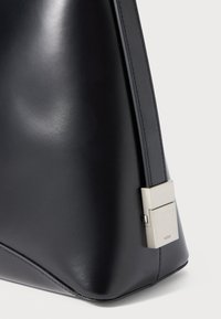 Black leather handbag with a structured design, featuring a silver-toned hardware accent and smooth texture. Sturdy stitched edges.