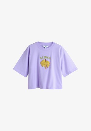 Lilla kortærmet croppet t-shirt med gul banangrafik og grøn "ALOHA" tekst på brystet.